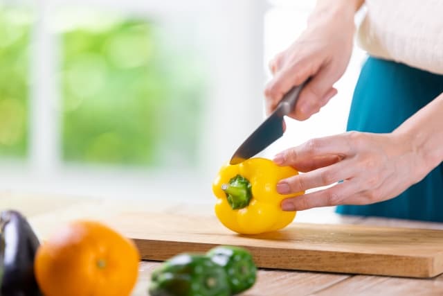 ピーマンを包丁でカットしている人