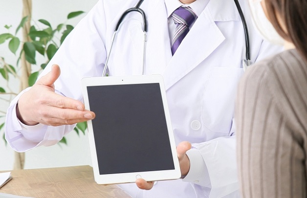 タブレットを見せて説明する医者