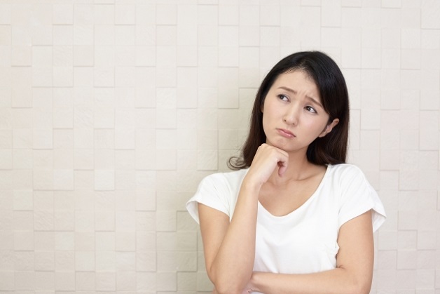 顎に手を当てて悩んでいる女性